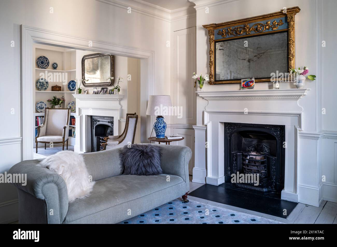 Grey sofa with gilt framed mirror above Georgian fireplace in Greenwich townhouse, London, UK Stock Photo