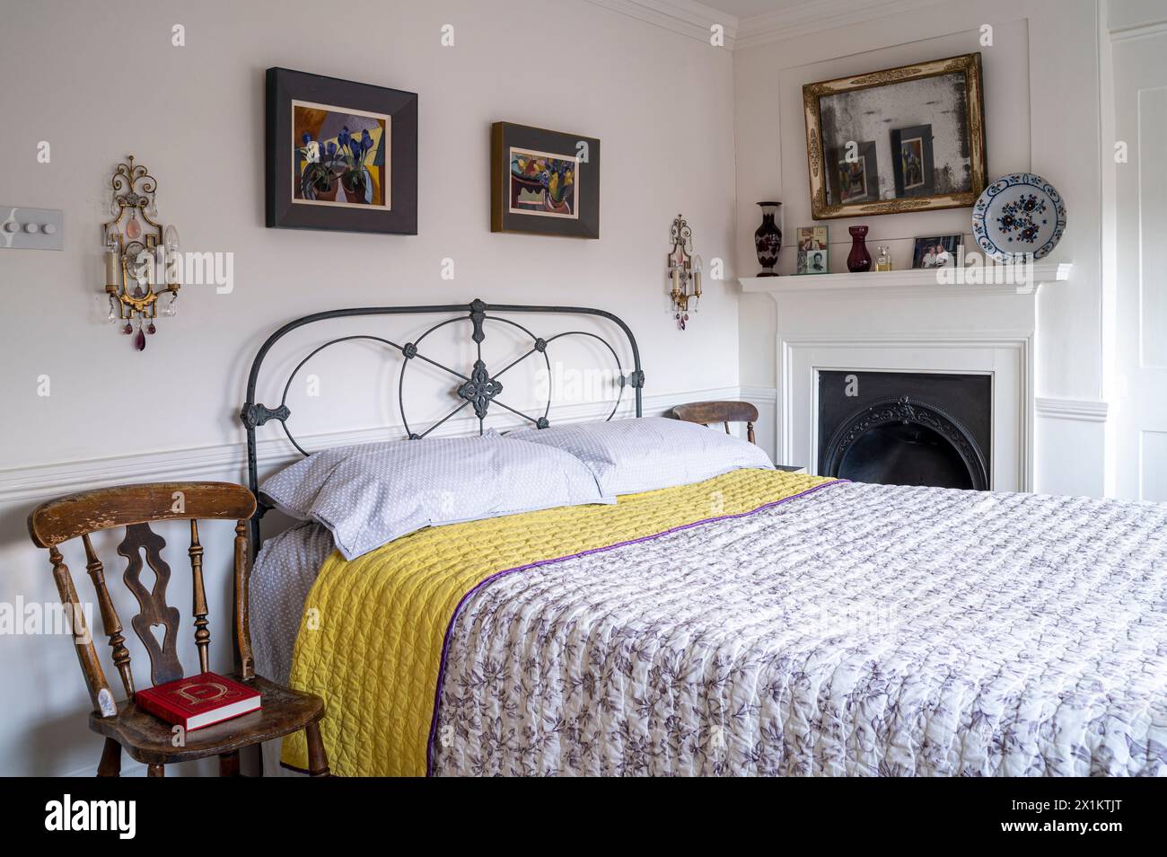 Old fashioned metal framed bed with framed prints in stylish Georgian Greenwich townhouse, London, UK Stock Photo