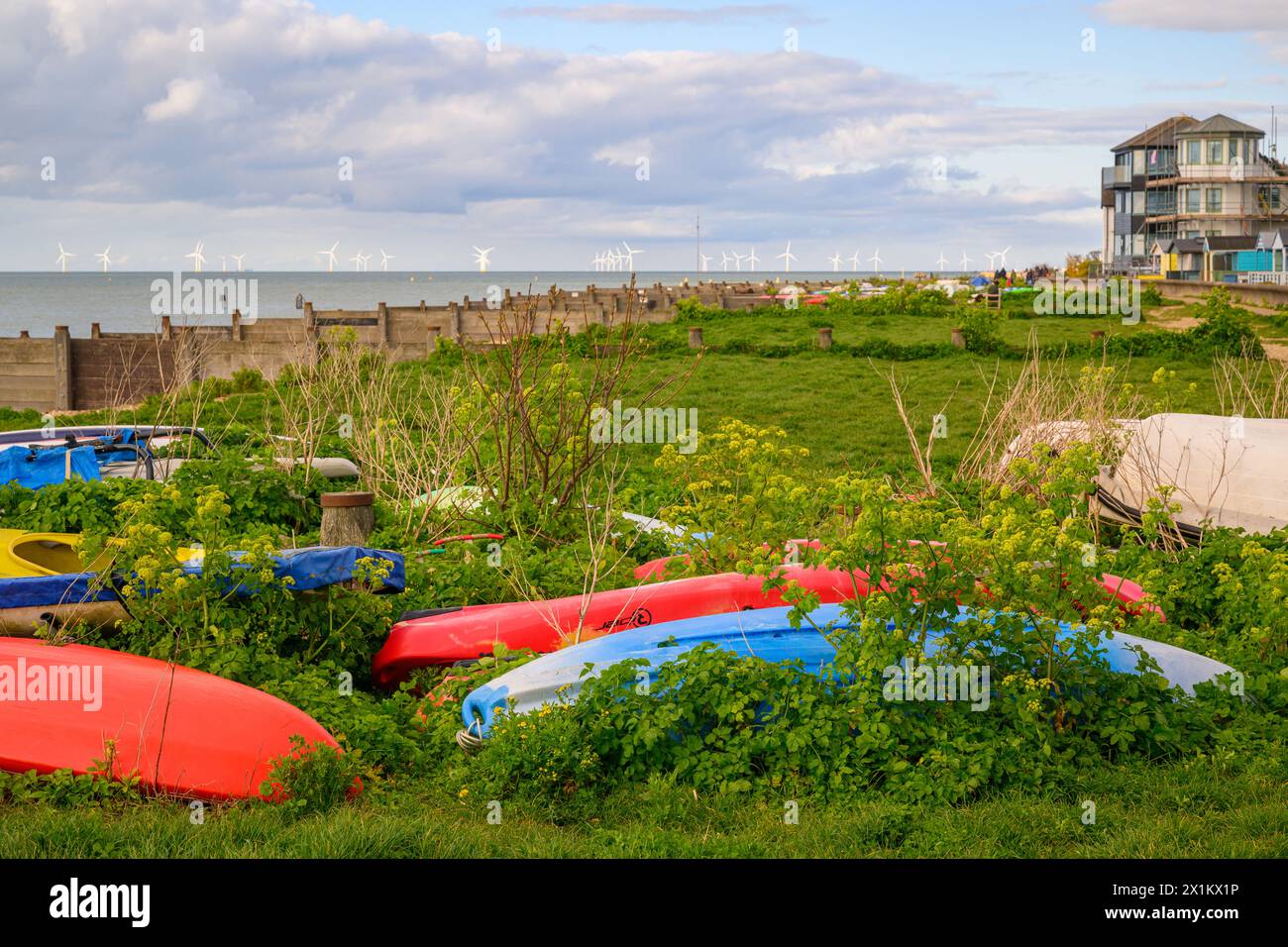 Abandoned boats on the beach with the offshore wind farm in the background, Whitstable, Kent, England Stock Photo