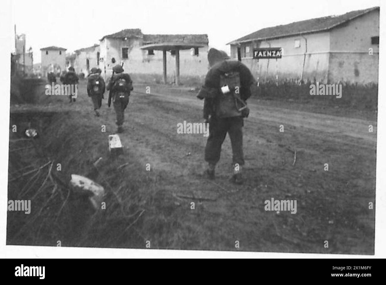 Eighth Army troops advance past the entrance sign to Faenza following its capture, under British Army operations during World War II. Stock Photo