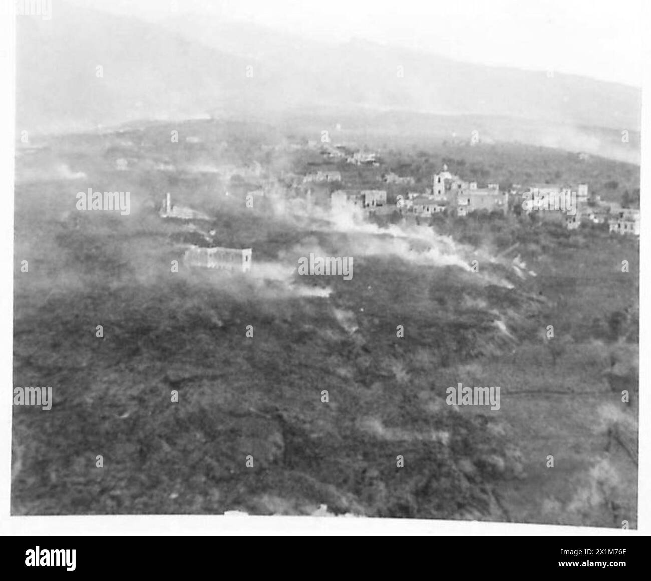 ITALY : AERIAL VIEW OF ERUPTION OF VESUVIUS - Photographs taken from an aerial O.P. 'plane of the Royal Artillery, showing houses with walls pushed over, and some with just their chimneys showing engulfed in the still smoking stream of lava, British Army Stock Photo