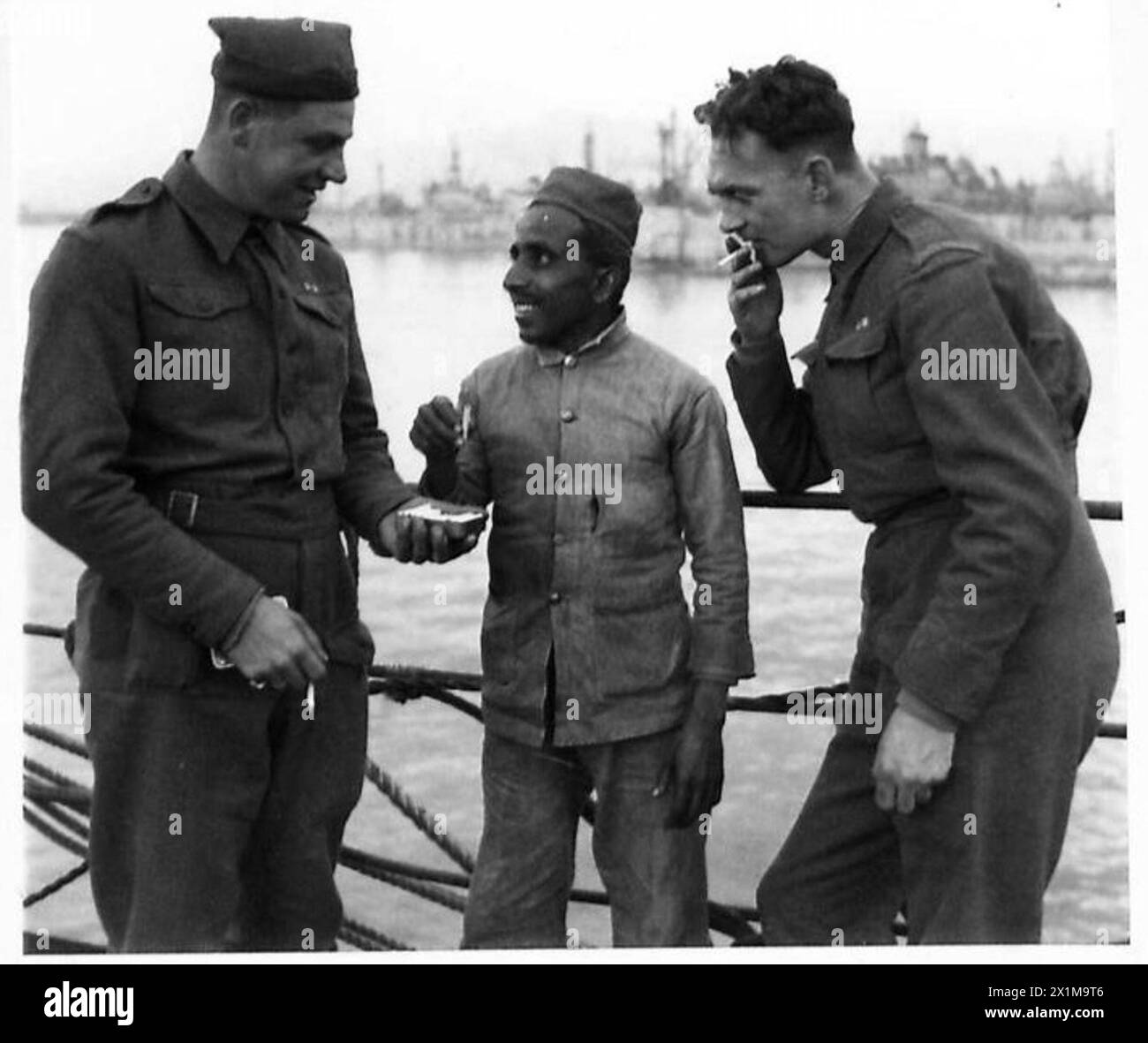 ITALY : FIFTH ARMYPREPARATIONS FOR NEW ALLIED LANDING - Guardsmen chat with an Indian deck hand. Left to right:- Gdsmn Lawrence Dodd of 116 Northumberland Terrace, Liverpool, 5. Nazar Khan, the Indian deckhand Gdsmn William Kelly of 4, Nutbourne Street, Queens Park London, W.10, British Army Stock Photo