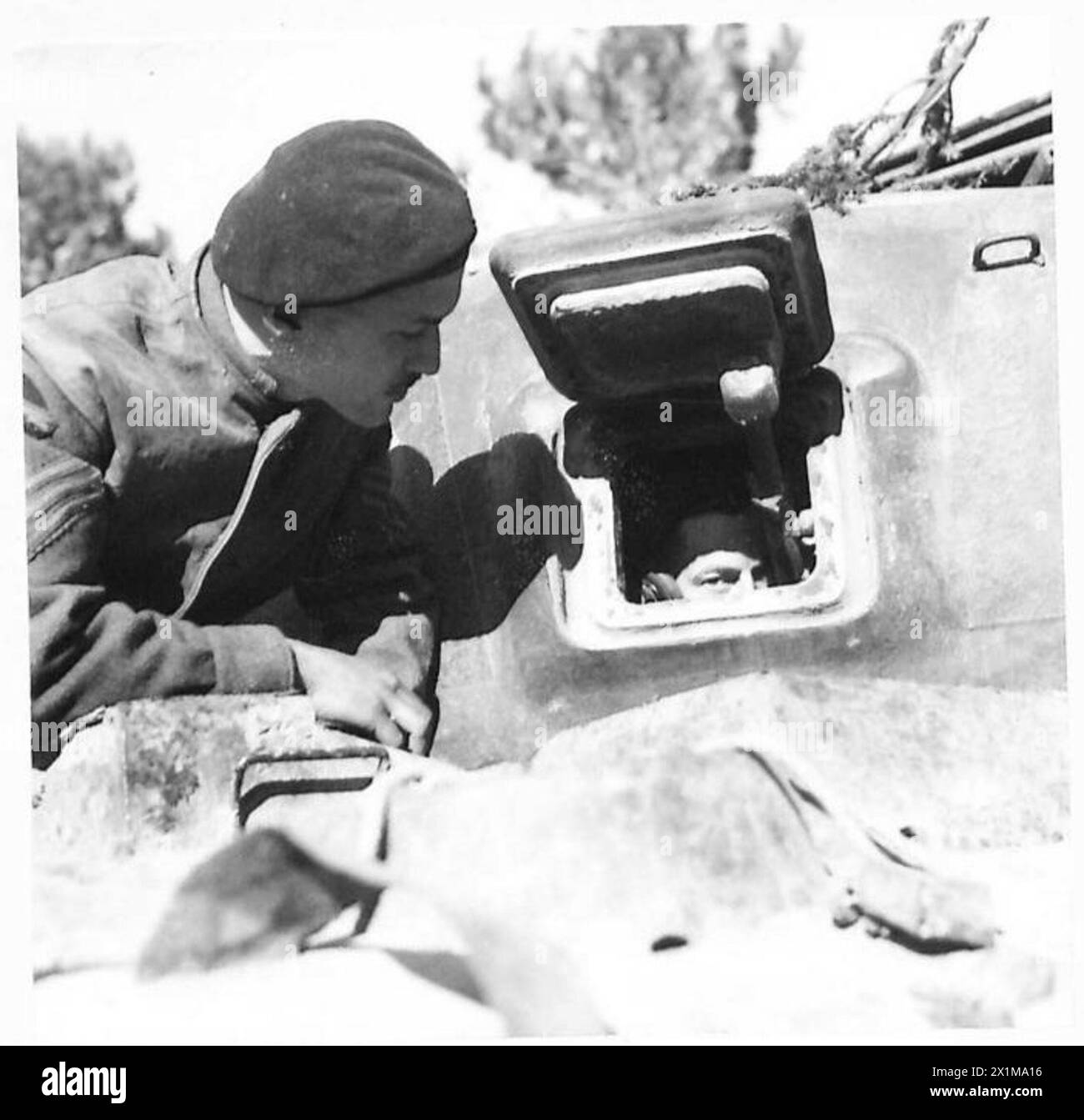 Sgt. Charette communicates with the wireless operator through the tank hatchway while discarding empty shell cases, British Army, Eighth Army in Italy. Stock Photo