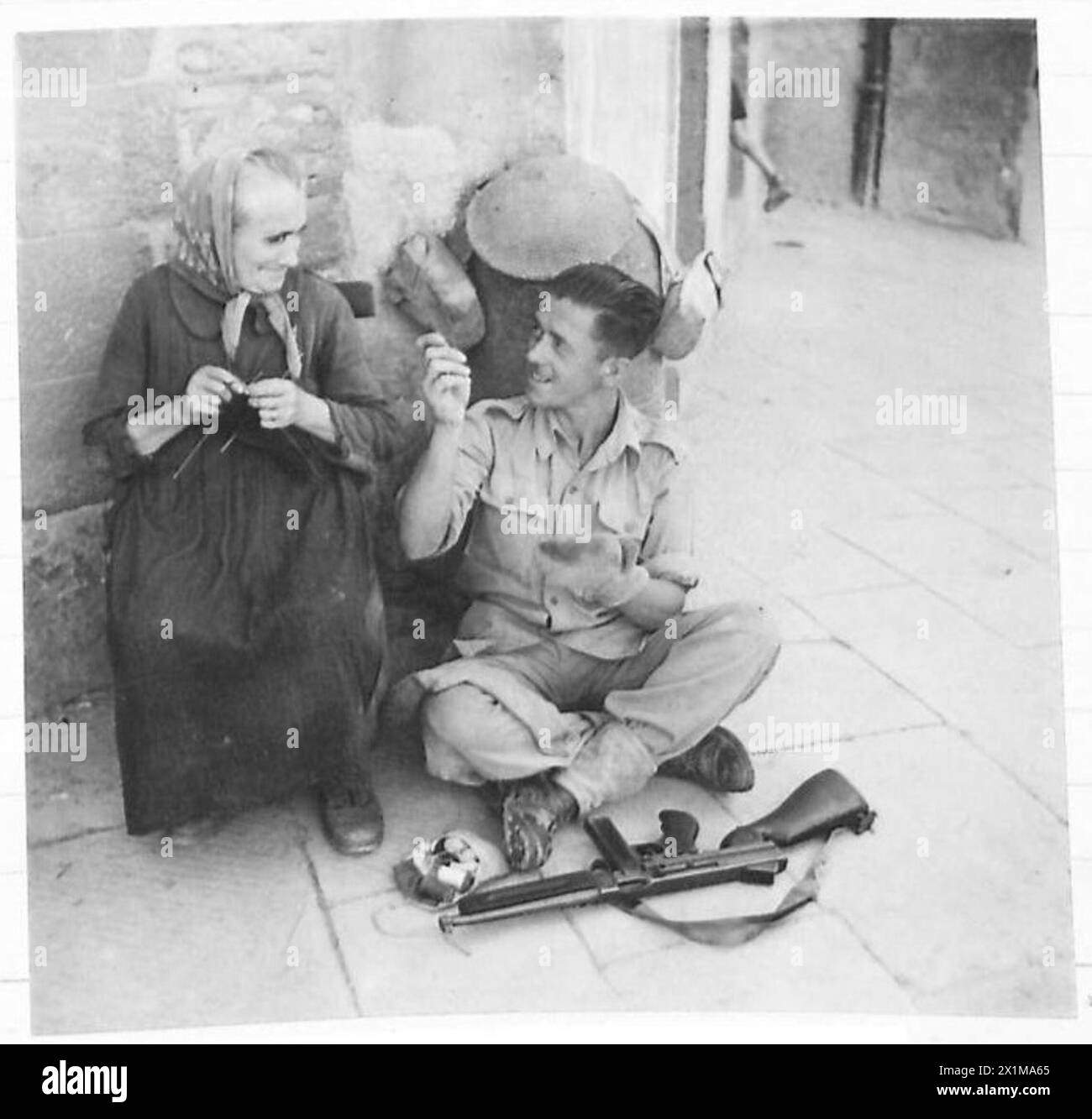 EIGHTH ARMY : VARIOUS - Rfn. Brighthouse of Preston makes friends with an old Italian woman while making some necessary running repairs, British Army Stock Photo