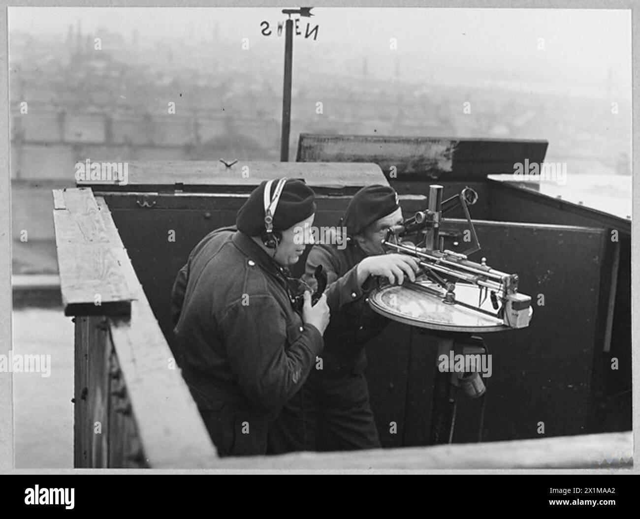 WITH THE ROYAL OBSERVER CORPS - Picture (issued 1944) shows - Two members of the Royal Observer Corps on duty at their roof top post in London. At the range and height finder is Observer Bert Couzens of East Ham, and reporting on the telephone to H.Q. is Observer Jim Shephard of Stratford, N., who joined the Corps in 1938, Royal Air Force Stock Photo