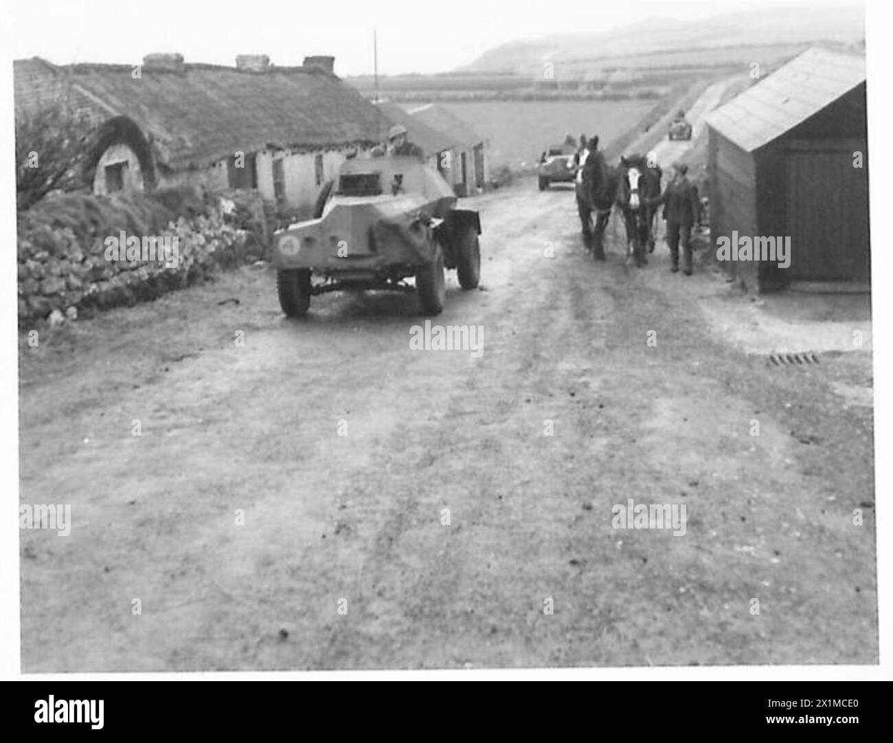 BRITISH FORCES IN NORTHERN IRELAND - Armoured cars (Humberettes) passing through a typical North of Ireland village. In the distance is the Giants Causeway, British Army Stock Photo