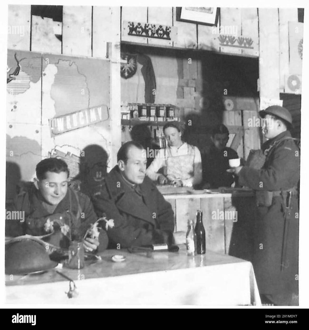 THE POLISH ARMY IN BRITAIN, 1940-1947 - Soldiers enjoying a cup of tea in the Brigade's canteen. Note a poster behind them showing occupied Poland with a caption reading: 'Wrócimy - We will come back'. Photograph taken at Cupar. A special series of photographs dealing with the domestic and social life of troops of the 1st Rifle Brigade (1st Polish Corps) in Scotland where the officers and men are firmly established favourites with the local people. Some of the young soldiers were attending universities in Poland when war broke out. On arrival in Britain they joined the Polish Forces and contin Stock Photo