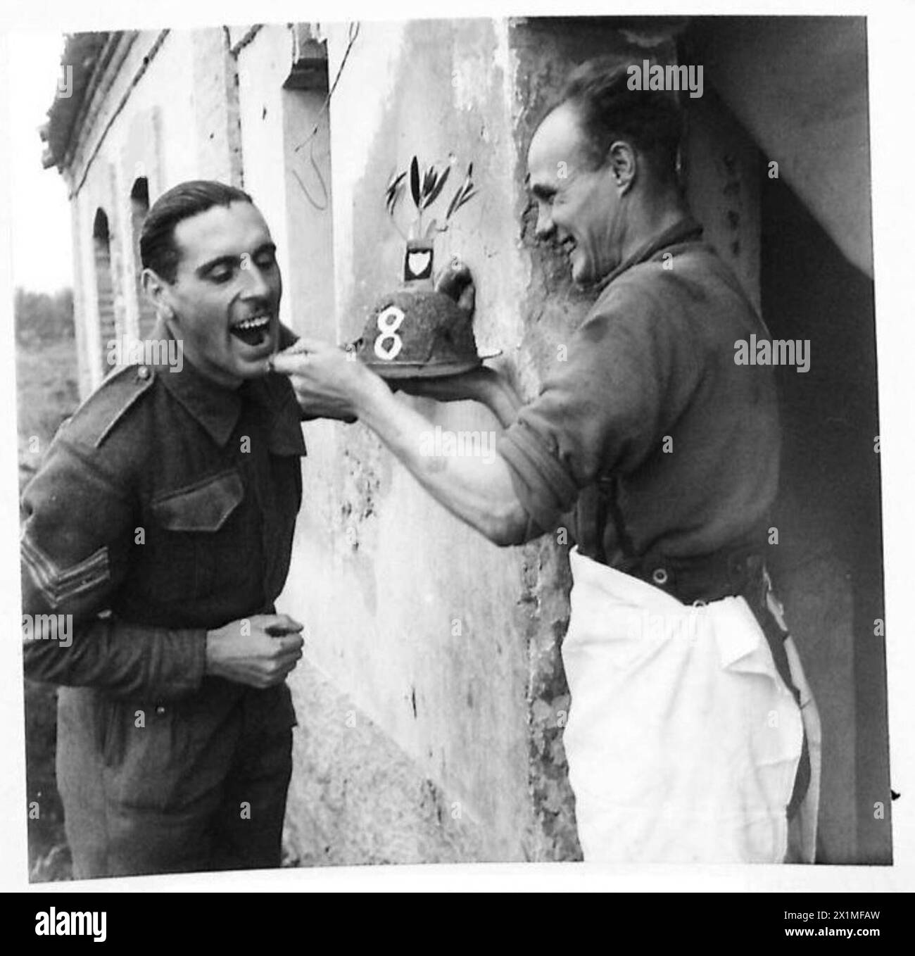 ITALY : EIGHT ARMYCHRISTMAS WITH THE TROOPS IN THE FIELD - Dvr. J.E. Insley of 2 Ducie Street, Clapham, London, gives Sgt. John Rooke, Royal Signals, of 295 Brompton Road, London, a taste of the sample Christmas fare, British Army Stock Photo