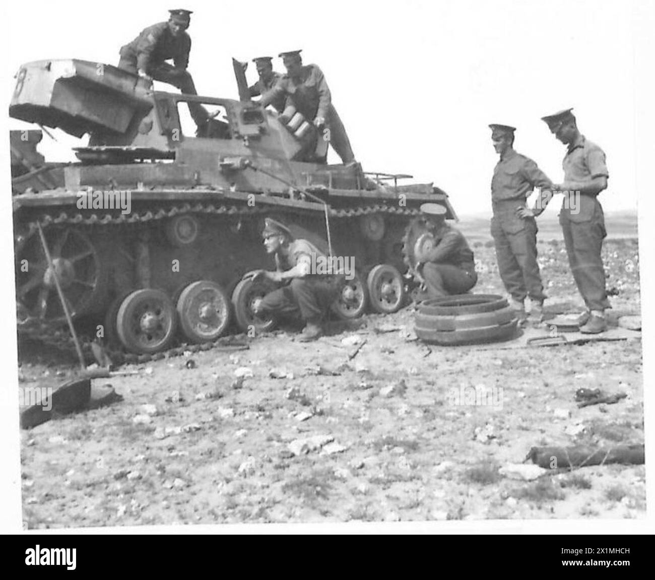 GUARDS SUCCESS AGAINST 15TH PANZER DIVISION IN NORTH AFRICA - Examining one of their hits. On tank are Sgt. G. Stevenson of Grovslot, Margfott, Cumberland, Cdmm.I. Fenwick of Dundee and Cpl. Bunyon of Kelty, Fifeshire, on ground are J.MacDonald of Edinburgh, D. Hindle of Anderton, Lancs. L/Cpl H.K.Little of Ayr and Cpl. A. Campbell, British Army Stock Photo