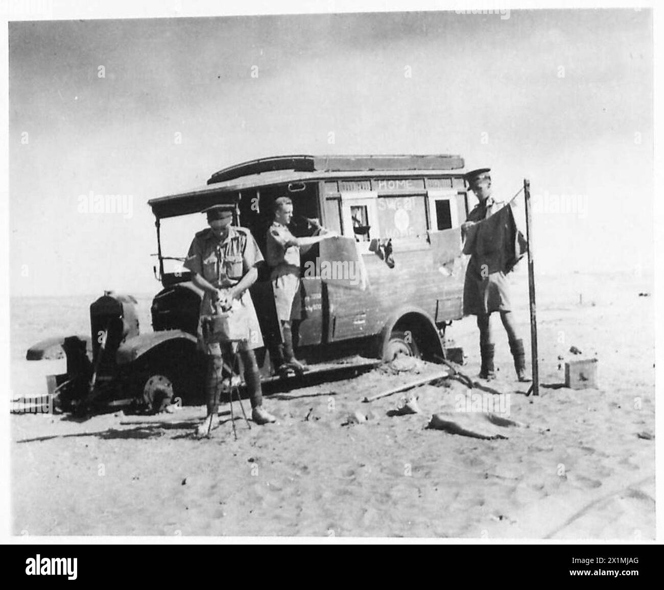 PHOTOGRAPHS TAKEN OF THE WORK OF THE MILITARY POLICE IN THE WESTERN DESERT - Washing day for the policemen outside their home - an Italian ambulance - called by them 'Home, sweet Home', British Army Stock Photo
