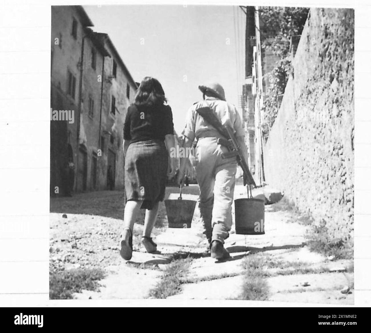 EIGHTH ARMY : VARIOUS - Rfn. W. Sabor of Manchester does his good turn of the day by carrying water for an Italian girl, British Army Stock Photo