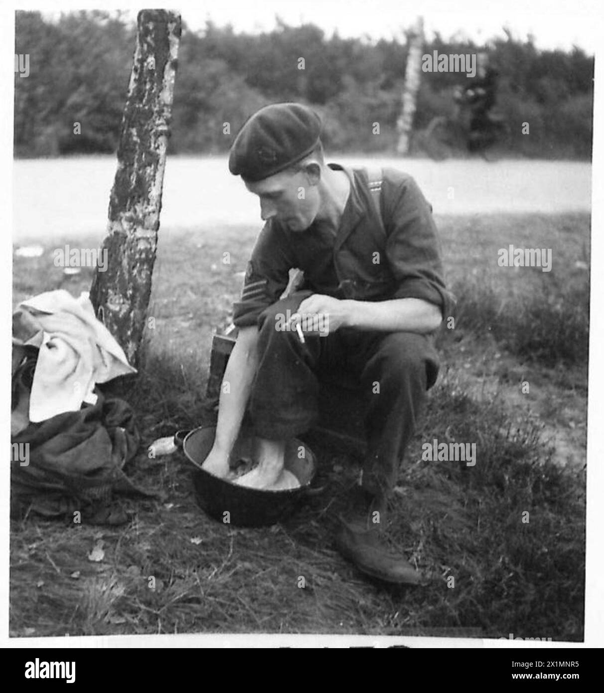 THE BRITISH ARMY IN NORTH-WEST EUROPE 1944-1945 - Sgt. H.G. Ashworth, Manchester, 1st. Airborne Div. washes his weary feet and takes a smoke, Stock Photo