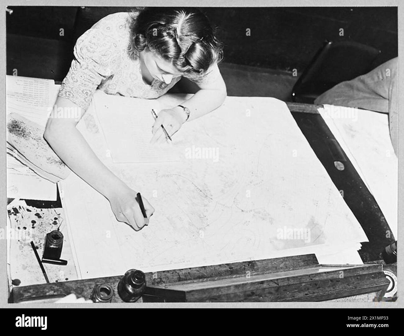 METEOROLOGICAL ORGANISATION OF THE AIR MINISTRY - 15746 Picture issued 1945 shows -Plotter Betty Davies prepares a chart for the forecaster on an outline map of Europe and athe Atlantic. The entries are made in the form of letters, figures and symbols in red or black ink, and give details of wind, temperature, cloud, abrometric pressure, weather and visibility. A new chart is prepared every three hours day and night, Royal Air Force Stock Photo