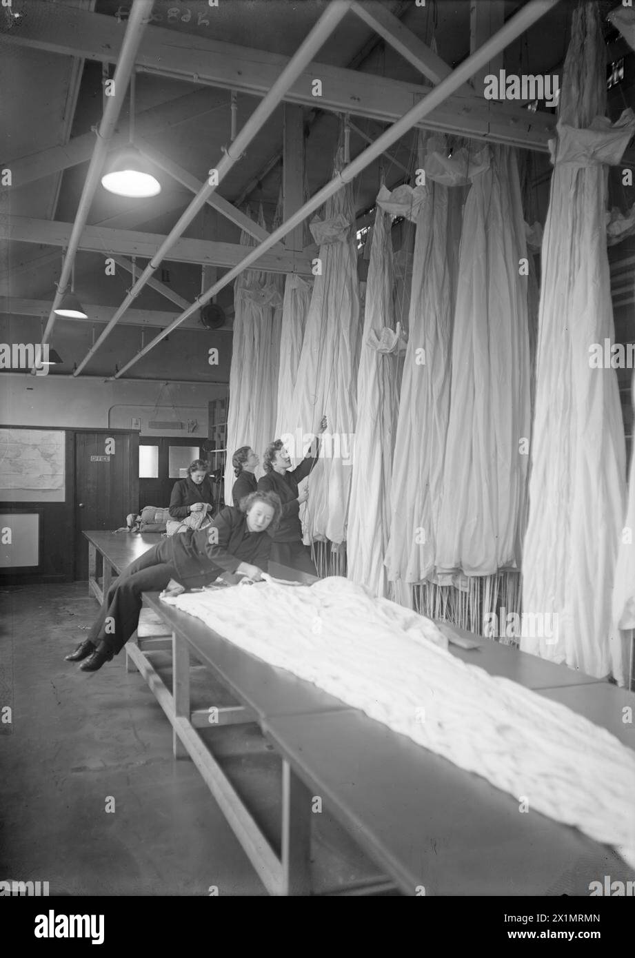 WREN PARACHUTE PACKERS. 20 JANUARY 1944, ROYAL NAVAL AIR STATION ST MERRYN, CORNWALL. - Wren parachute packers straightening out the silk folds before packing, Stock Photo