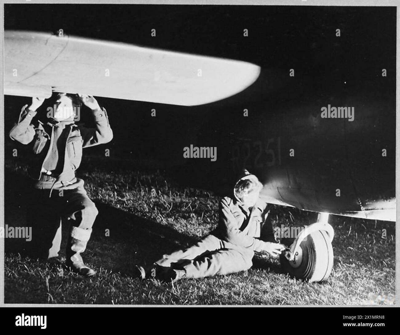 W.A.A.F. flight mechanics service an aircraft at night, performing