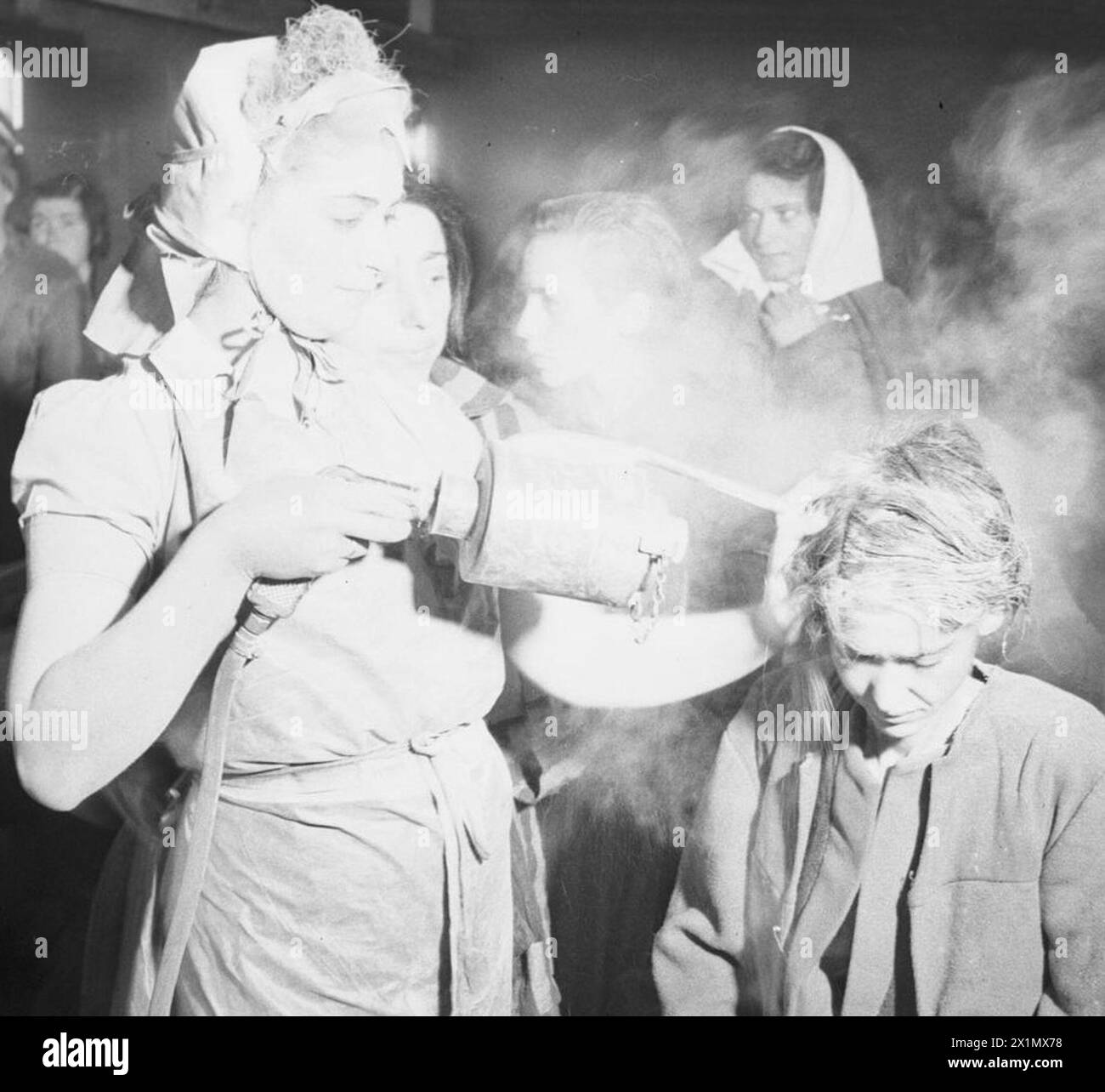 THE LIBERATION OF BERGEN-BELSEN CONCENTRATION CAMP, MAY 1945 - After dressing in clean clothes, a woman inmate is dusted with DDT powder to kill the lice which spread typhus. The dusting is done by other former camp inmates (many of whom were trained nurses before being interned) under the supervision of the Royal Army Medical Corps, British Army, Royal Army Medical Corps Stock Photo