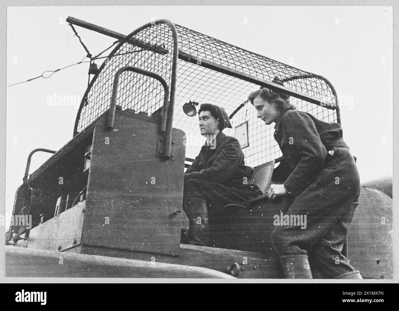 COURAGE OF WAAF BALLOON OPERATORS AT A LONDON BALLOON SITE. - During the raid by the Luftwaffe on London - 17th/18th January 1943 - two W.A.A.F. balloon operators carried on with their job bringing their balloon to required height in spite of the fact that two large high explosives bombs fell practically together. One bomb fell to the right and left of the winch respectively. The two W.A.A.F. balloon operators are 18 und 22 years old. Corporal May Dyson [left] and ACW Peggy Muncy Beeson of Essex (right) at work on their winch the following day. Corporal Dyson is 22 years old and ACW Beeson 18 Stock Photo
