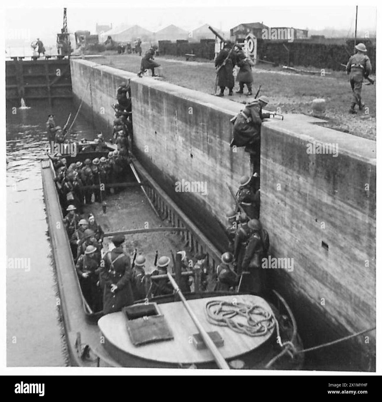 HOME GUARDS DEFEND INLAND WATERWAYS - Scaling the lock by means of iron run ladders, Home Guards leave the barge and reinforce the lock defences, British Army Stock Photo
