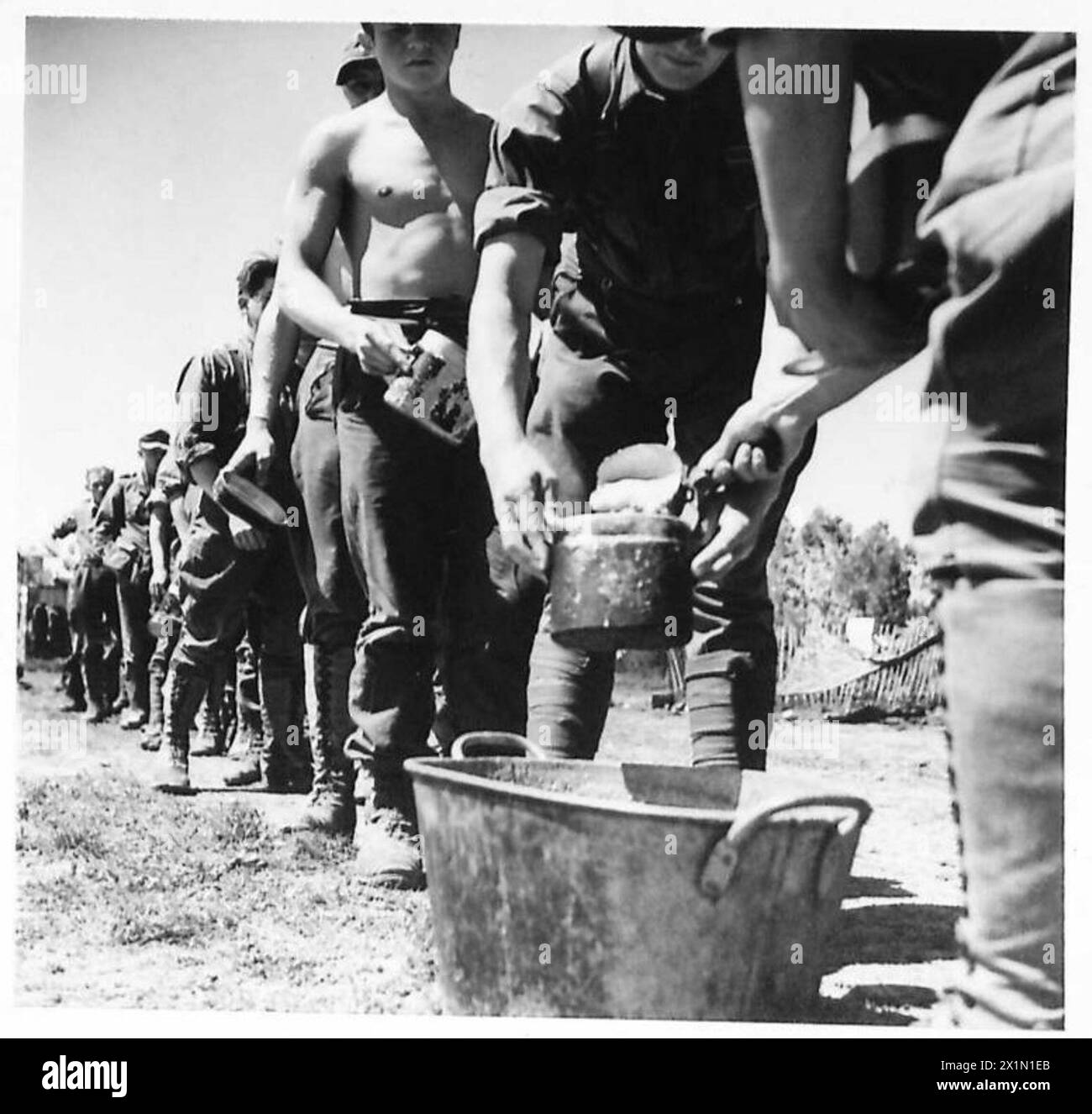 WITH THE FIRST ARMY (VARIOUS) - Served by one of their own men, a paratroop sergeant, prisoners line up for their mid-day meal in the P.O.W. camp at Souk el Khemis, British Army Stock Photo