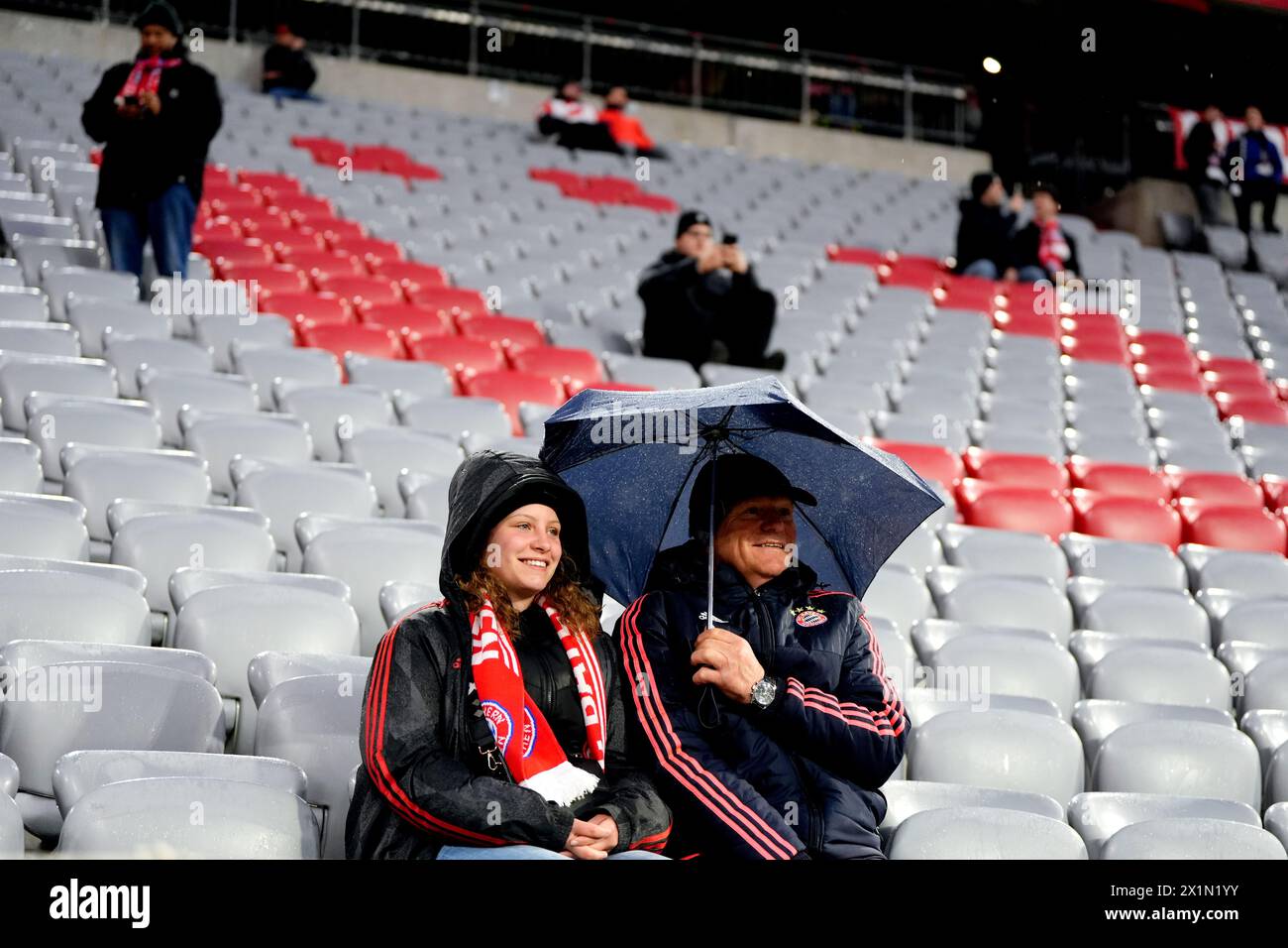 Bayern Munich fans shelter from the rain in the stands ahead of the UEFA Champions League quarter-final, second leg match at the Allianz Arena, Munich. Picture date: Wednesday April 17, 2024. Stock Photo