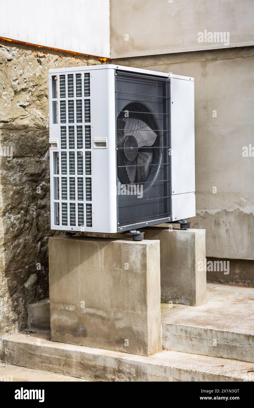 Air source heat pump installed outside of old renovated house, green renewable energy concept of heat pump Stock Photo