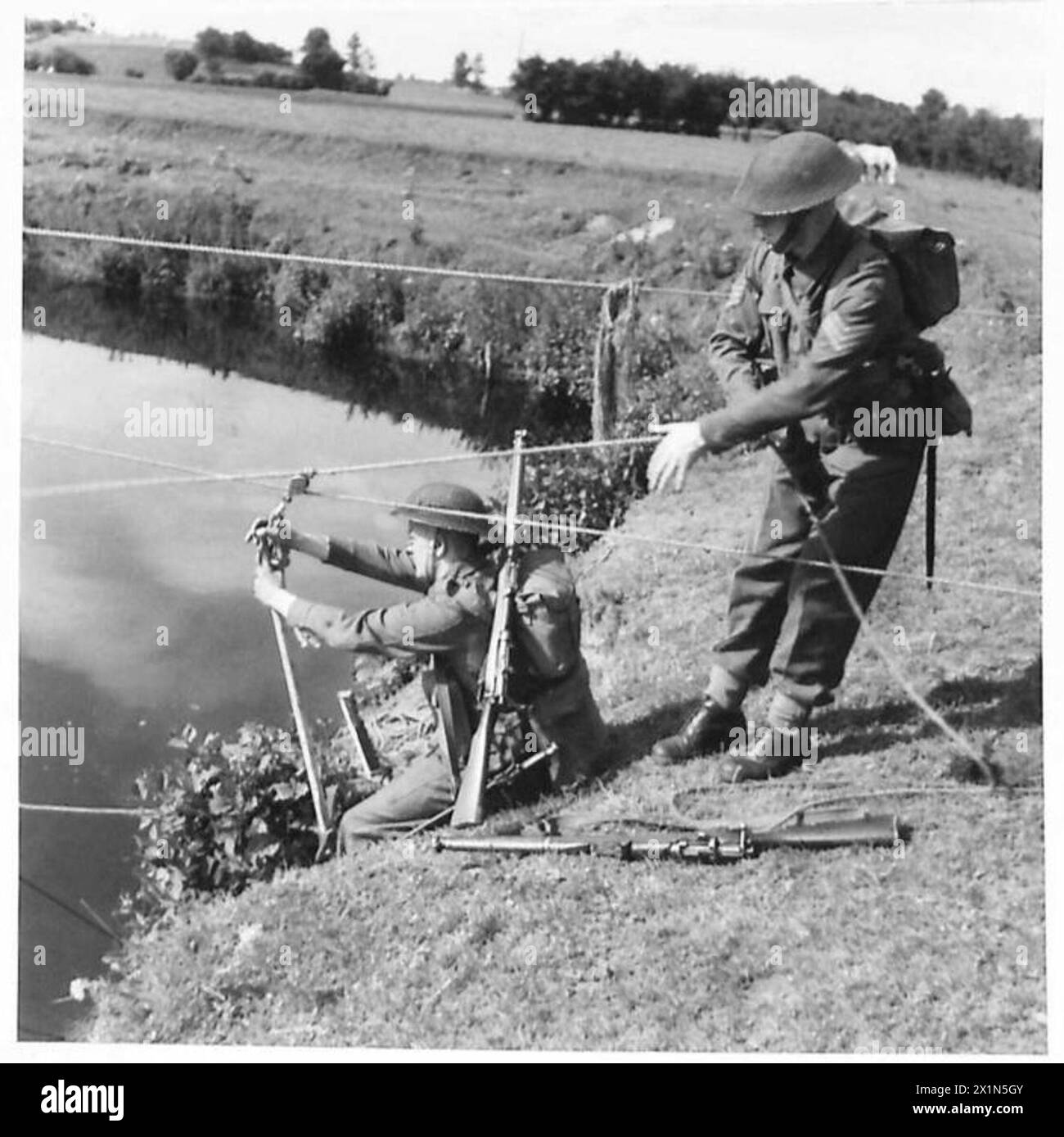 GETTING ACROSS A RIVER - A pick axe suspended from the pulley makes a first class seat on which to be hauled across the river, British Army Stock Photo