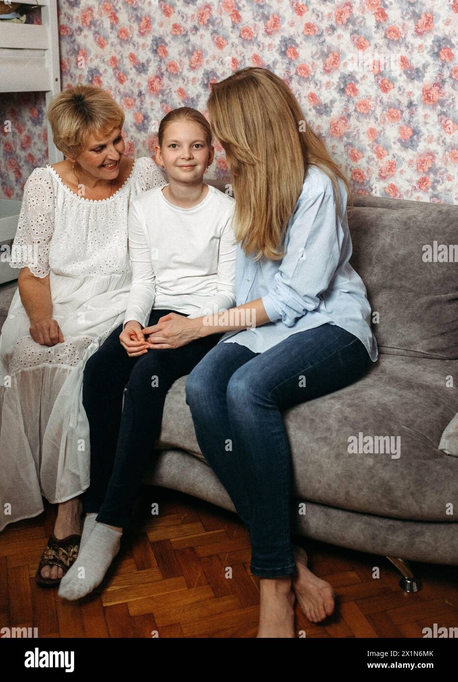 Two women and a child are sitting on a soft sofa facing each other