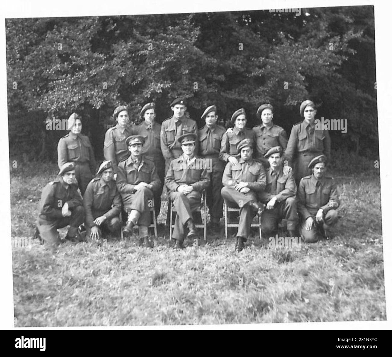 ARAB, ETC. EX-PRISONERS OF WAR IN ENGLAND - Staff Group Seated centre front - left to right - Lieutenant El Khalidi, Captain Anhoury, A.C. CSM Tarhuni, O. Remainder - left to right - Private S. Kaladgian Private J. Abu-Shaar Private A. Masri Sergeant N. Issa Private A. Abbas Private F.R. Chivers Private A. Mortada Sergeant A. Thakidin Lance Corporal I. Farrah Private S. Zakarira Private A. Sheihab Private A. Nijm, British Army Stock Photo