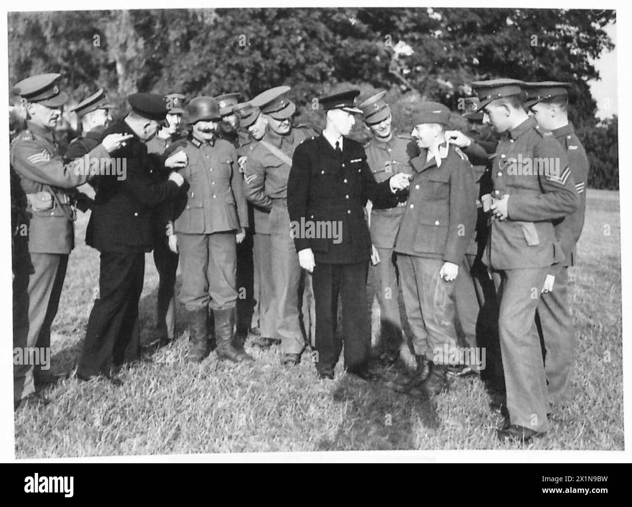 GERMAN PRISONERS INTERROGATION DEMONSTRATION - Members of the Civil and Military Police examining the uniforms after the demonstration, British Army Stock Photo