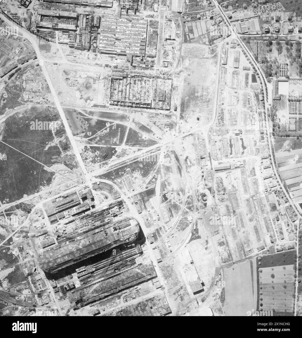 ROYAL AIR FORCE: OPERATIONS BY THE PHOTOGRAPHIC RECONNAISSANCE UNITS, 1939-1945. - Vertical photographic-reconnaissance aerial taken over Friedrichshafen, Germany, following the raid by 322 aircraft of Bomber Command on the night of 27/28 April 1944. Several large buildings have been destroyed in the Maybach Motorenbau GmBH engine factory (top). There is also severe damage to buildings of the Luftshiffbau Zeppelin, including the giant airship hangar (lower left), and group of 60 huts adjacent to this plant are two-thirds destroyed (middle right). This was an outstandingly successful attack, la Stock Photo