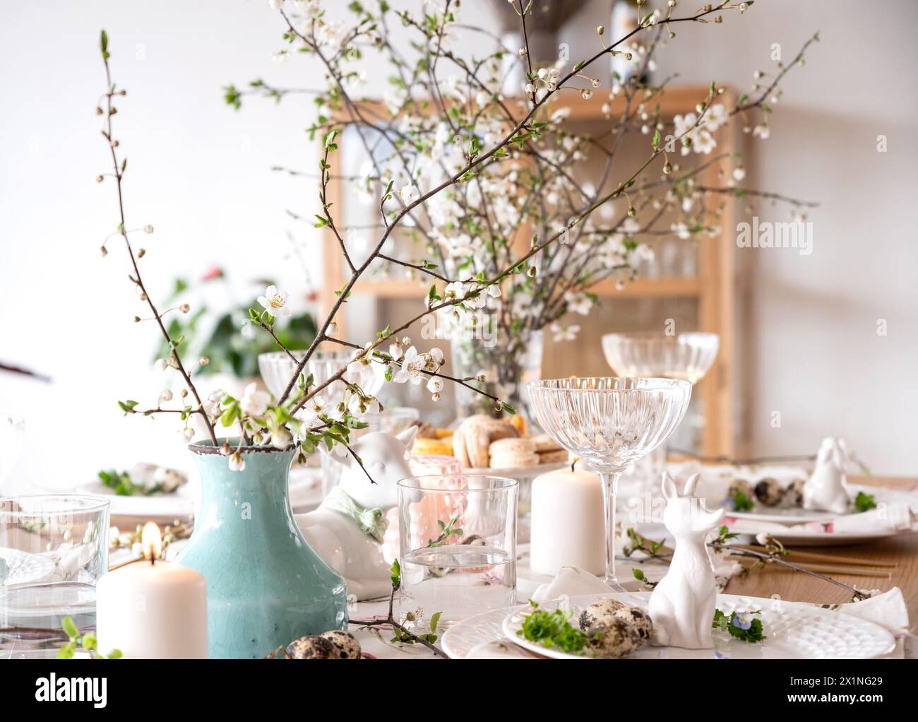 Spring Easter decor. Easter table setting. Flowers and dishes and candles for a festive dinner.  Stock Photo