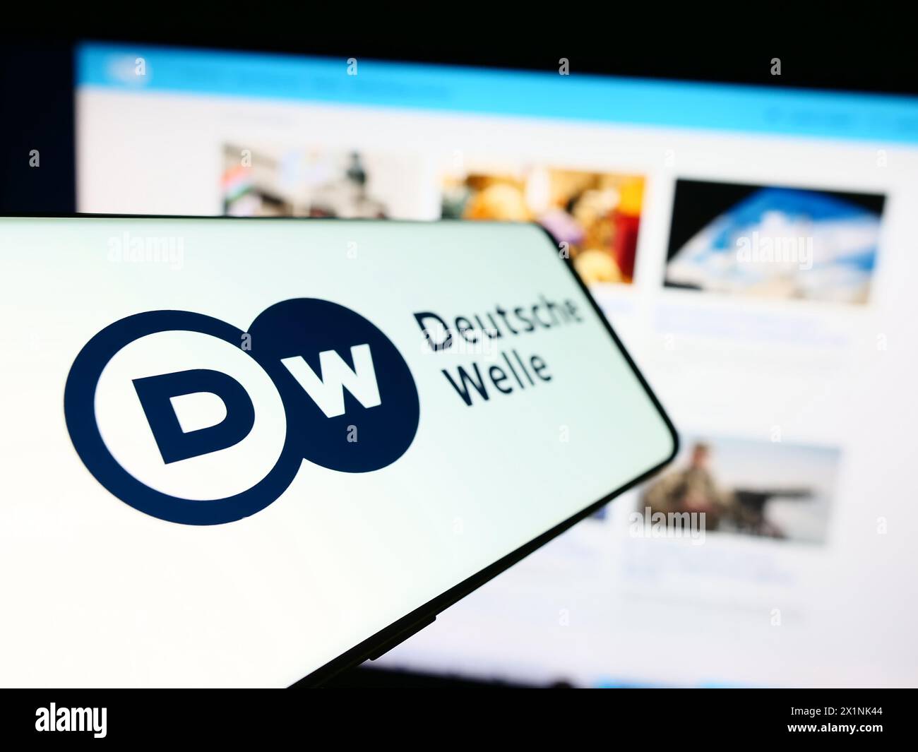 Mobile phone with logo of German state-owned broadcaster Deutsche Welle (DW) in front of website. Focus on left of phone display. Stock Photo
