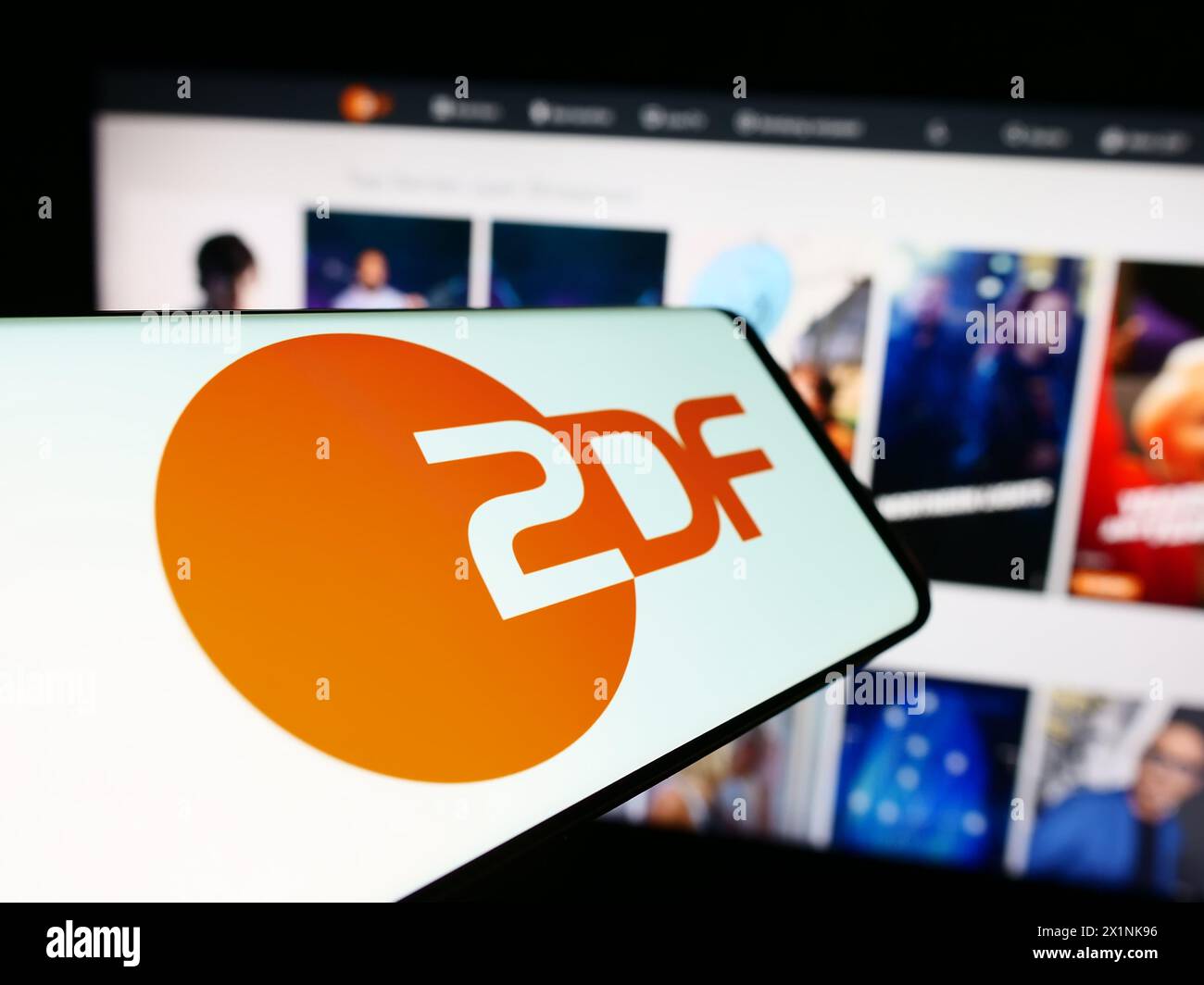 Cellphone with logo of television broadcaster Zweites Deutsches Fernsehen (ZDF) in front of website. Focus on center of phone display. Stock Photo