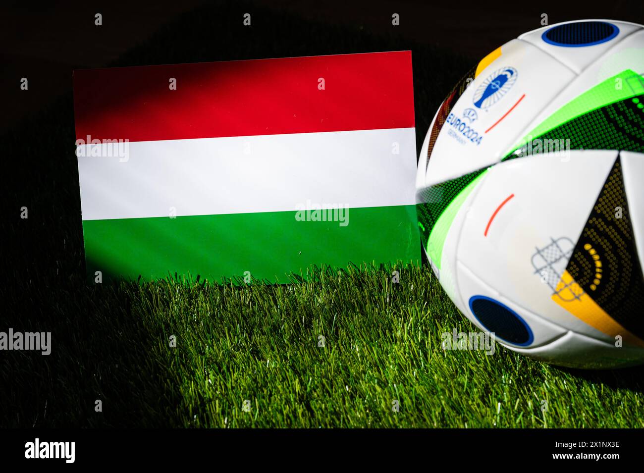 BERLIN, GERMANY, APRIL 17, 2024: Hungary national flag and official soccer ball of Euro 2024 football tournament in Germany placed on green grass. Bla Stock Photo