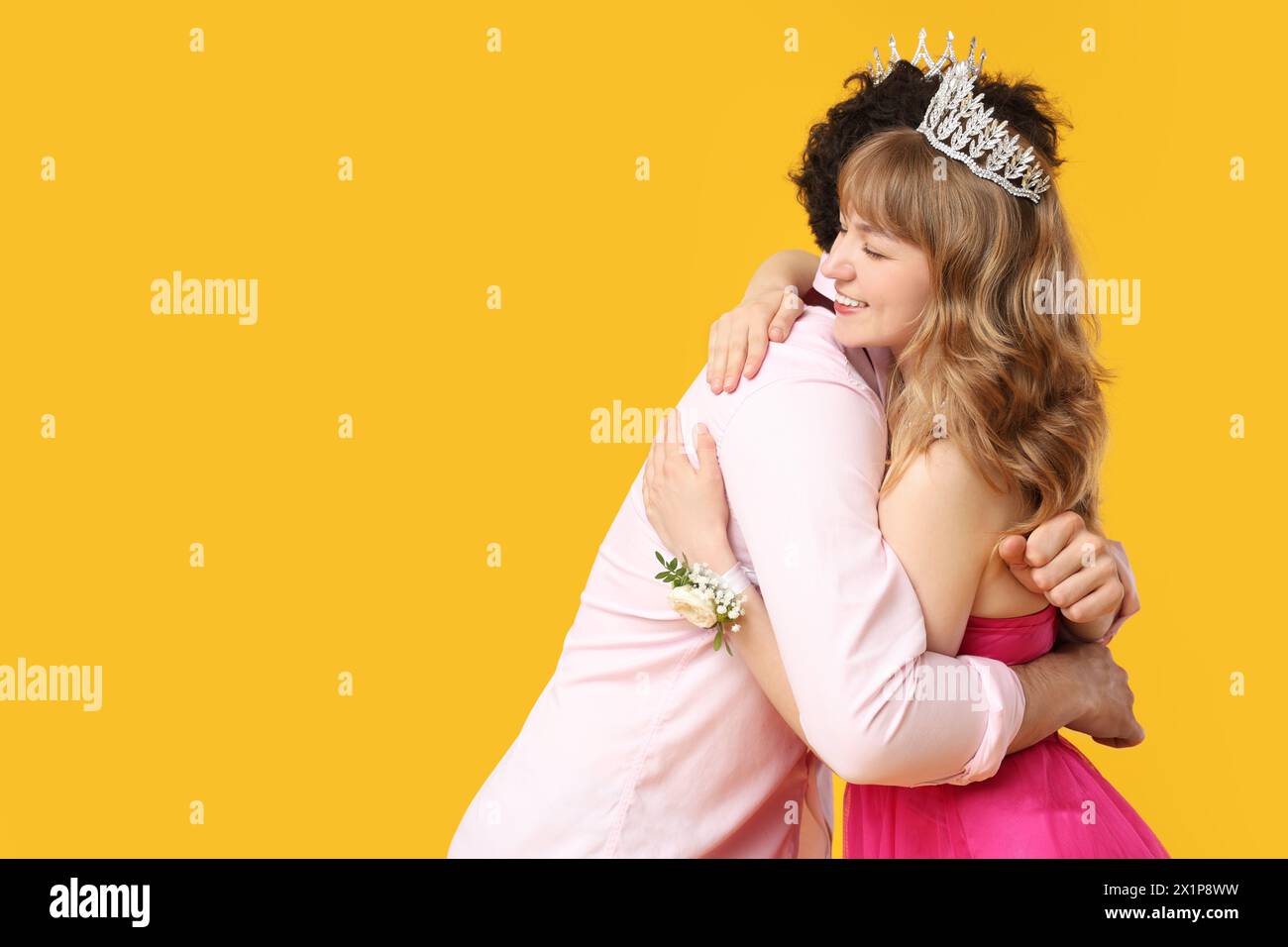 Happy prom couple hugging on yellow background Stock Photo