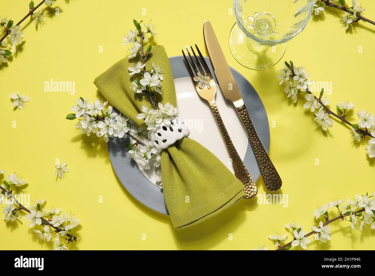 Beautiful table setting with blossoming branches on yellow background Stock Photo