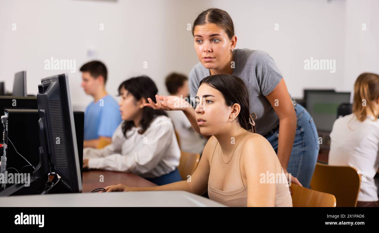 Smart female teenager giving a clue to the female co learner while she