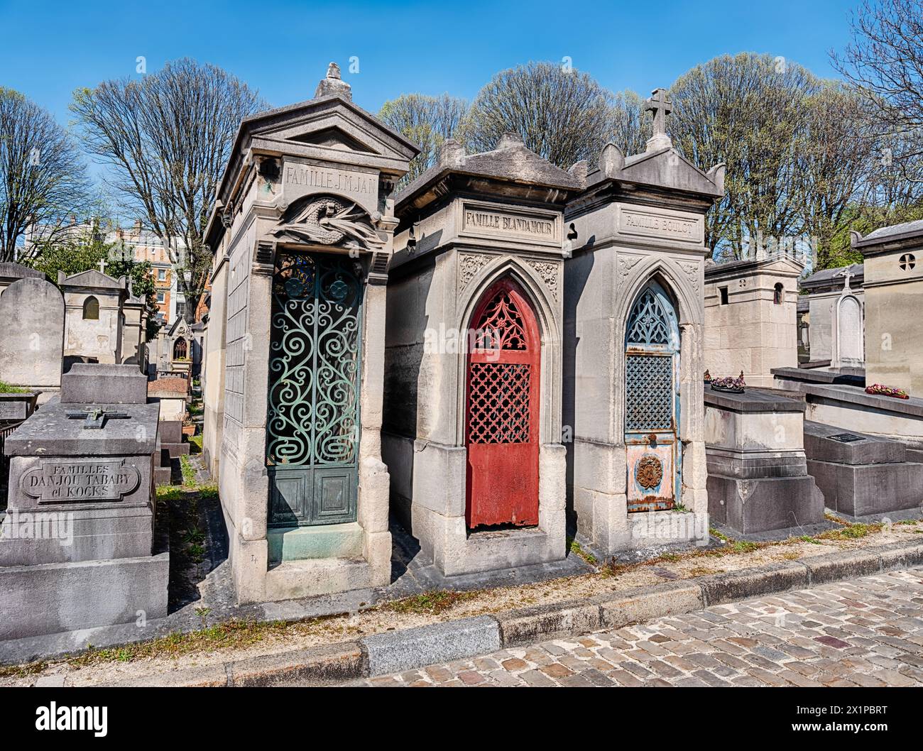 PARIS, FRANCE - APRIL 5, 2023: Three family crypts with green, red, and blue metal doors stand together in the Pere Lachaise Cemetery in Paris. Stock Photo