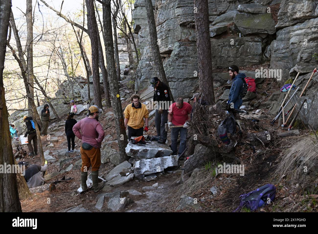 A trail maintenance crew works to remove a large rock that fell from the cliff onto the trail below at Pilot Mountain State Park in North Carolina. Stock Photo