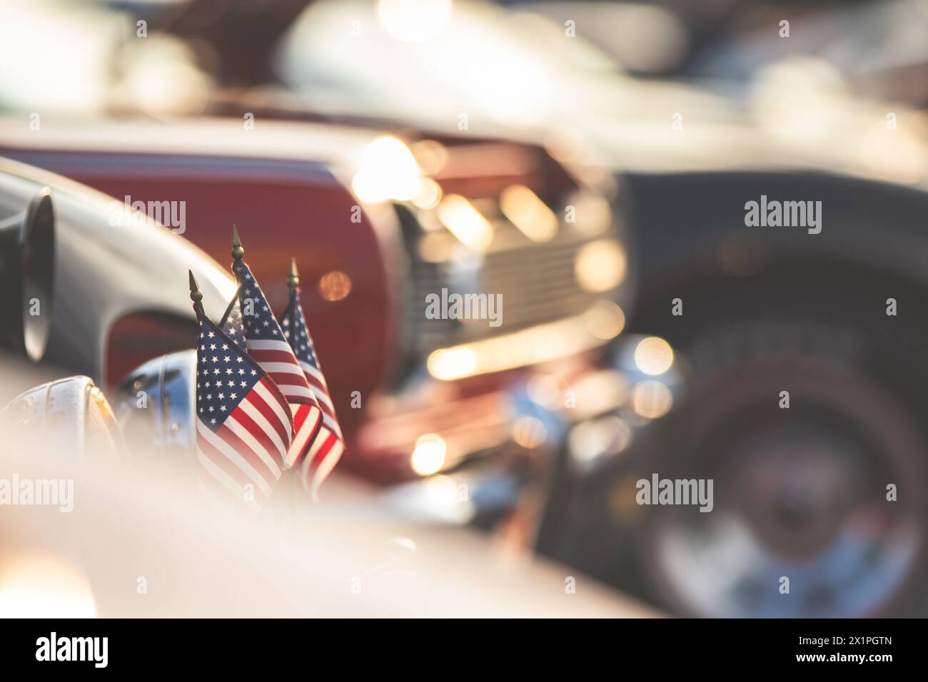 Small American flags on with a collection of classic American hot rods. Stock Photo