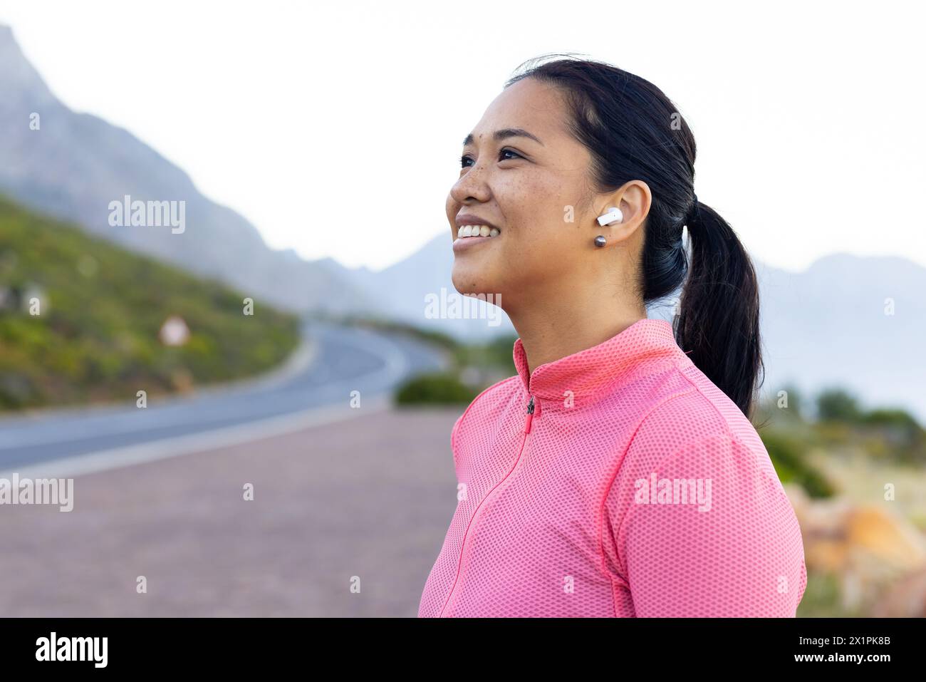 A biracial female hiker wearing earphones is enjoying nature, copy space Stock Photo