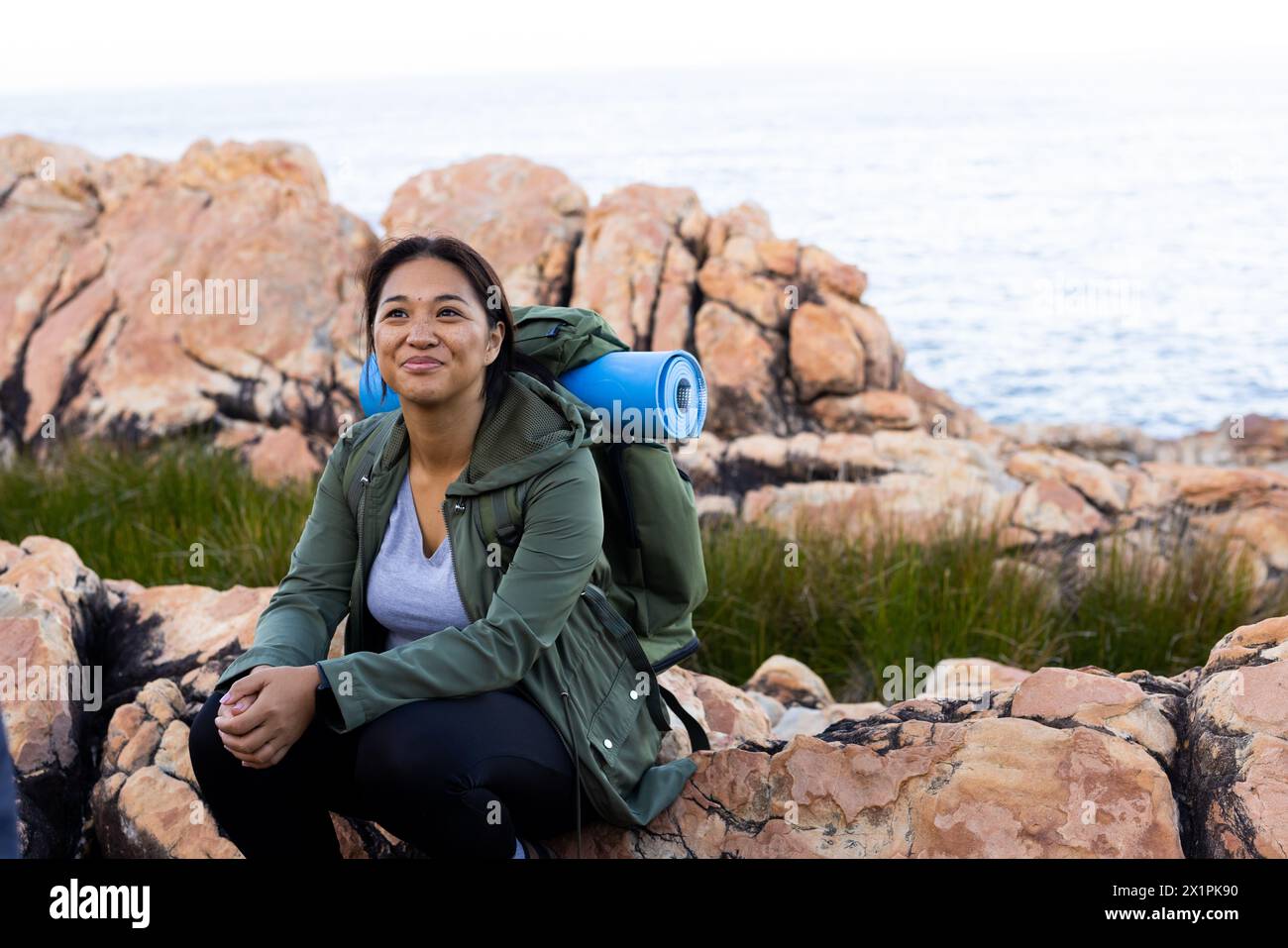 Biracial female hiker sitting on rocks, enjoying nature, copy space Stock Photo
