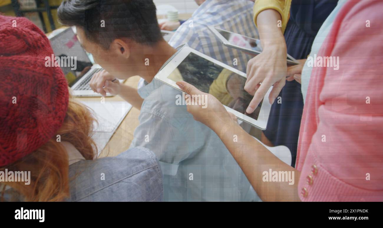 Group of diverse friends looking at tablet and laptop, collaborating Stock Photo