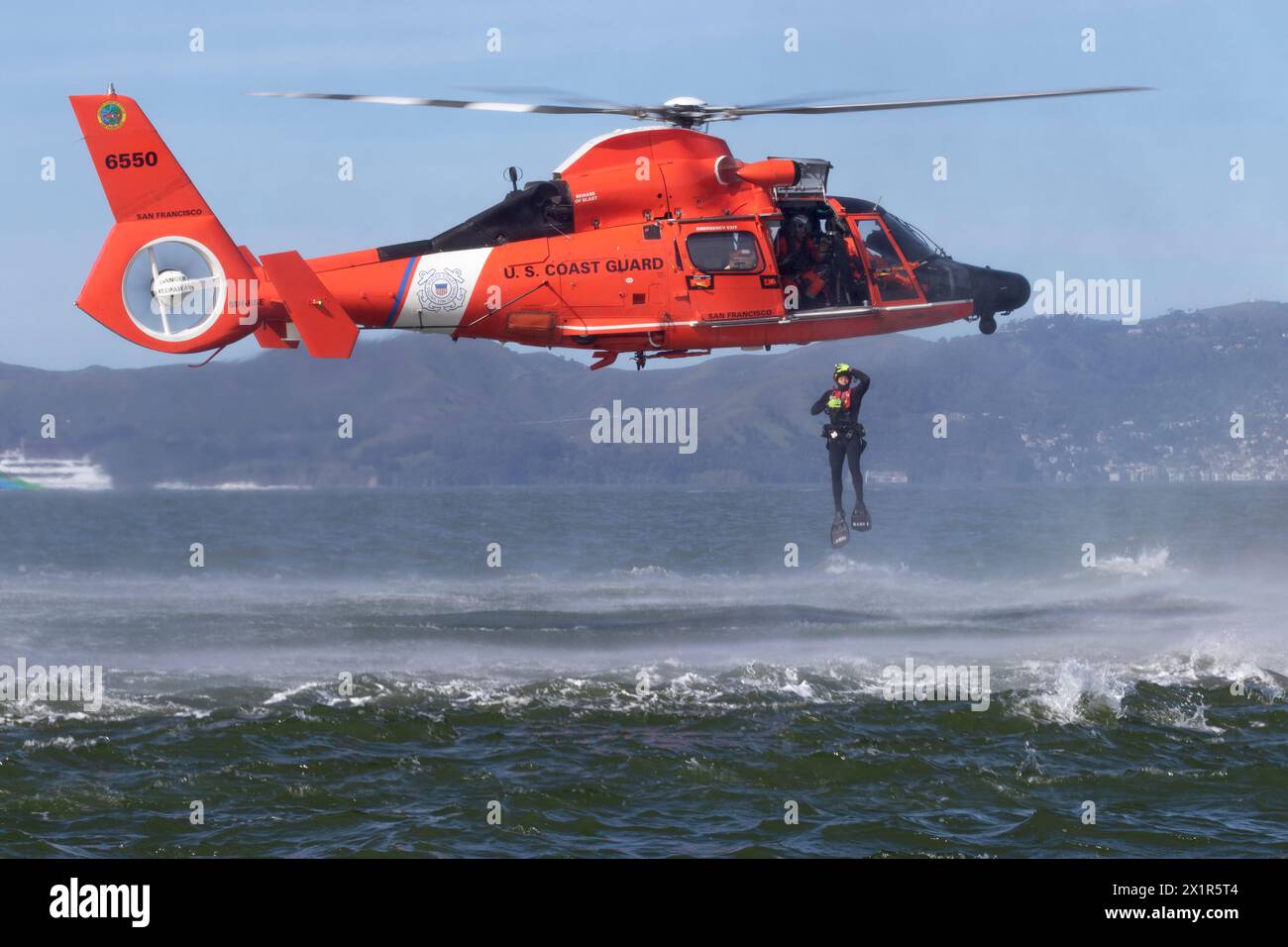 Coast Guard rescue swimmer drops from a hovering MH-65E Dolphin Helicopter into San Francisco Bay during training exercises. Stock Photo