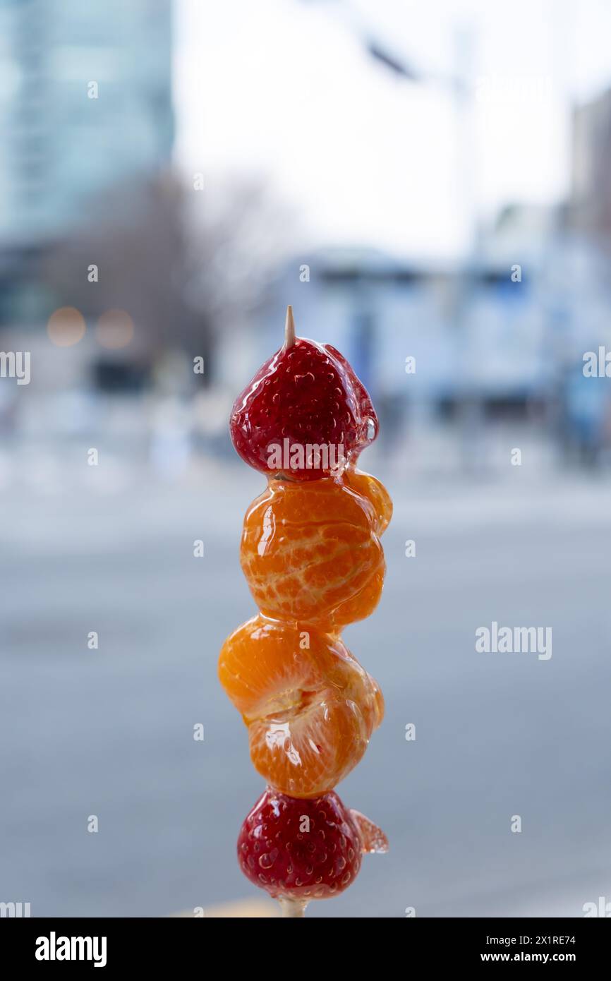 Strawberry and orange Tanghulu or Tang Hulu. It is a fruit dipped with sugar coating on a skewer. It is a traditional Northern Chinese snack. Stock Photo