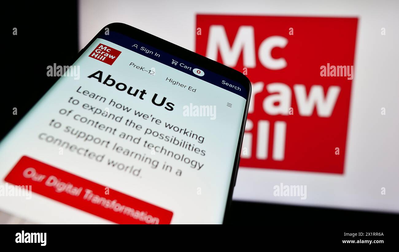 Mobile phone with website of US publishing company McGraw Hill LLC in front of business logo. Focus on top-left of phone display. Stock Photo