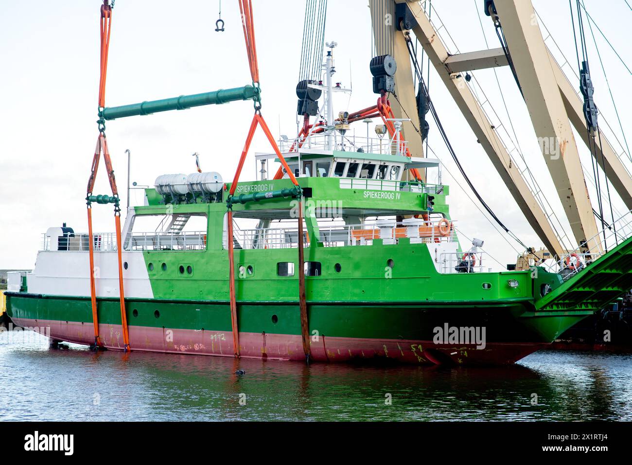Neuharlingersiel, Germany. 18th Apr, 2024. The floating crane 'Enak' lifts the ferry 'Spiekeroog IV' back into the harbor basin. The 300-ton ship, which is used for ferry services to the East Frisian island of Spiekeroog, had drifted away from its berth during the storm 'Zoltan' in December 2023 and onto a parking area in the harbour. Credit: Hauke-Christian Dittrich/dpa/Alamy Live News Stock Photo