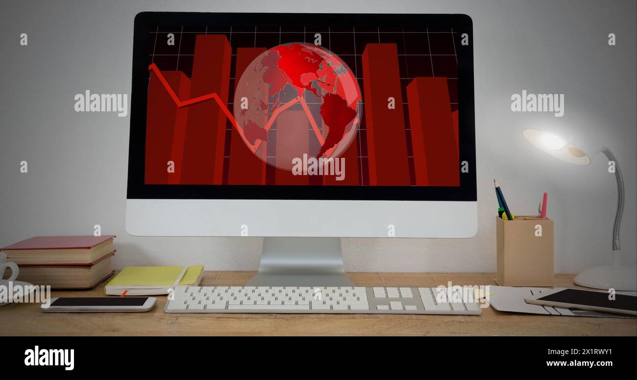 A computer screen displaying red world map and graphs sits on a desk Stock Photo