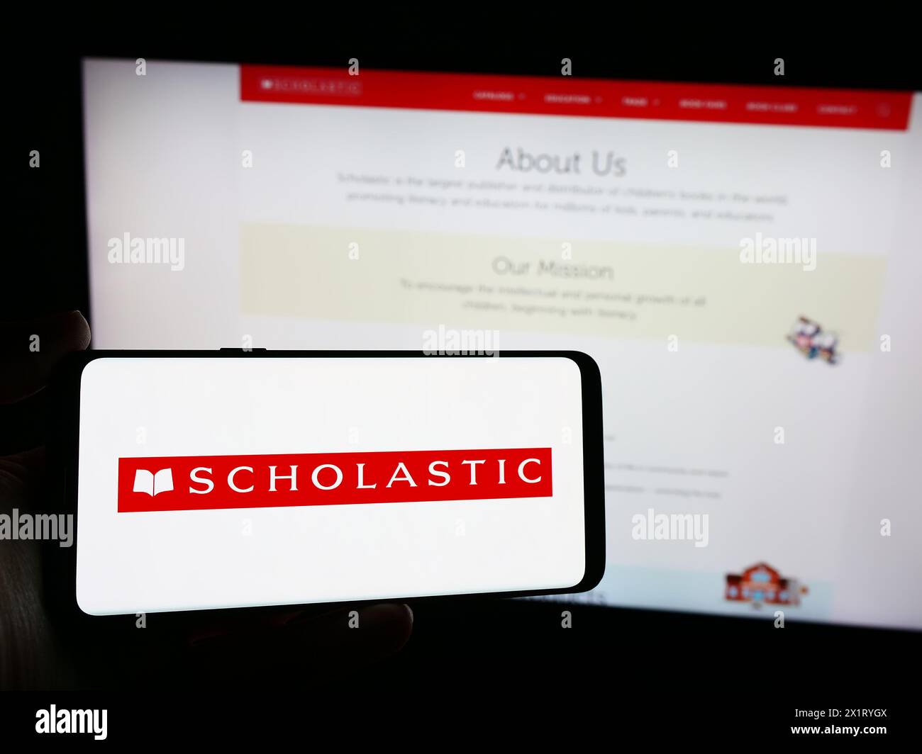 Person holding smartphone with logo of US publishing company Scholastic Corporation in front of website. Focus on phone display. Stock Photo