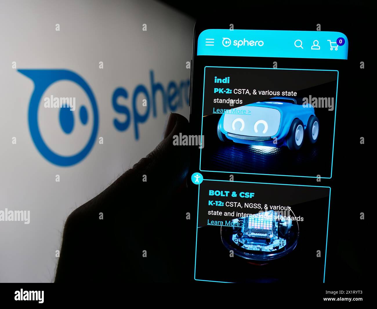 Person holding smartphone with webpage of US educational technology company Sphero Inc. in front of logo. Focus on center of phone display. Stock Photo